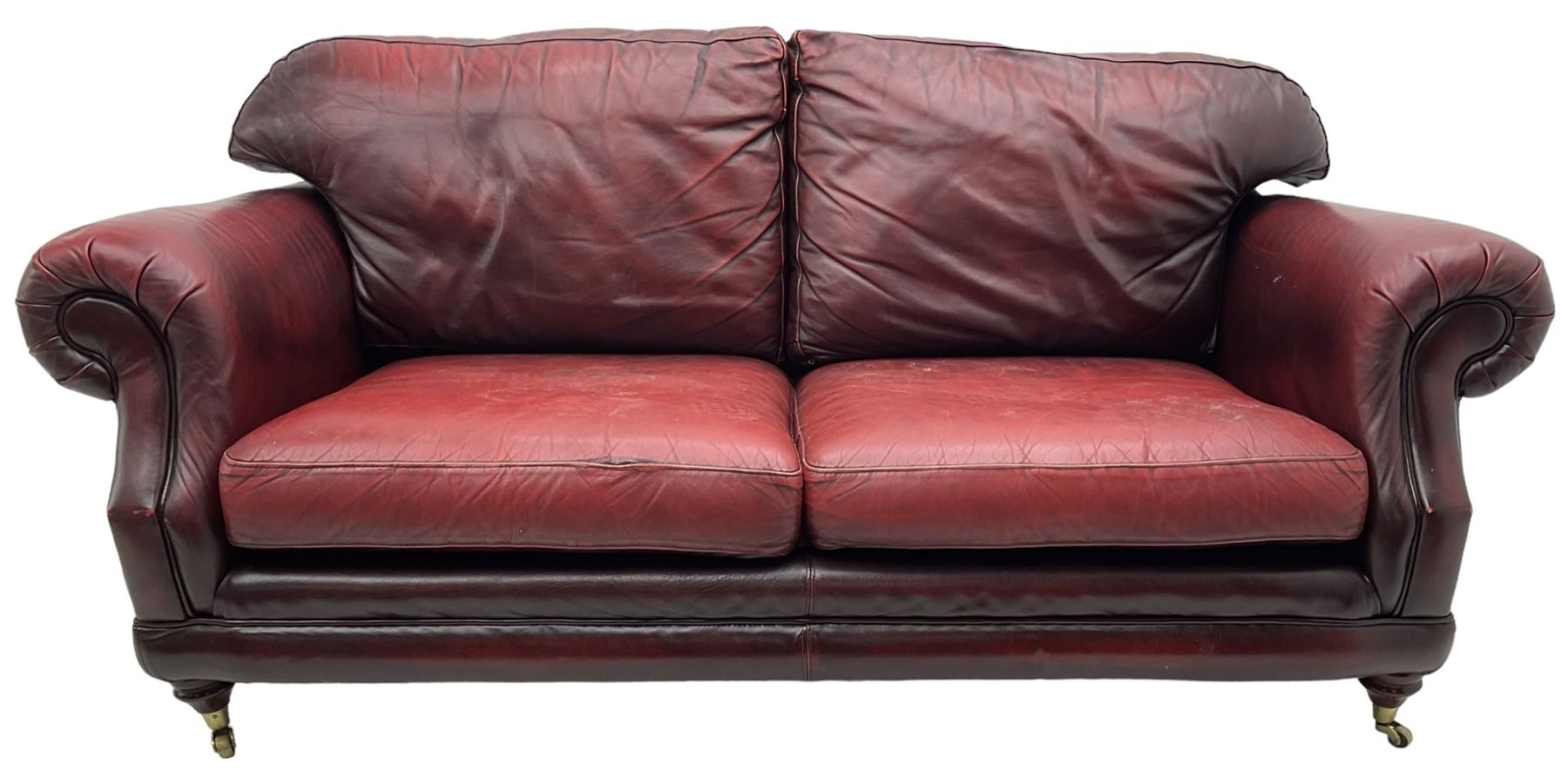 Thomas Lloyd - three-piece lounge suite, comprising of traditional shape two seat sofa (W190cm H80cm) and a pair of wingback armchairs (W100cm H91cm), each with rolled arms over turned supports with brass castors, upholstered in oxblood red leather