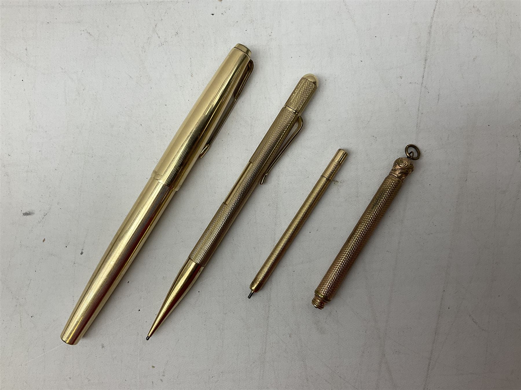 9ct gold propelling pencil with engine turned decoration and vacant cartouche, by S J Rose & Son, stamped 375, L12cm, together with a Parker 12ct rolled gold fountain pen, and two rose gold engine turned propelling pencils to include a rose gold example