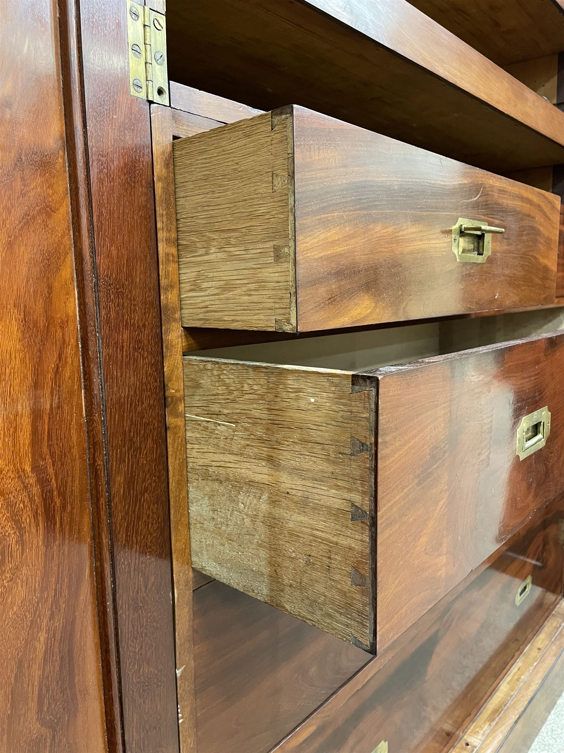 19th century figured mahogany quadruple breakfront press wardrobe, projecting cornice with banded frieze over arch panelled doors, the interior fitted with three sliding trays over two short and three long graduating drawers with recessed brass handles, flanked by two hanging cupboards with hooks