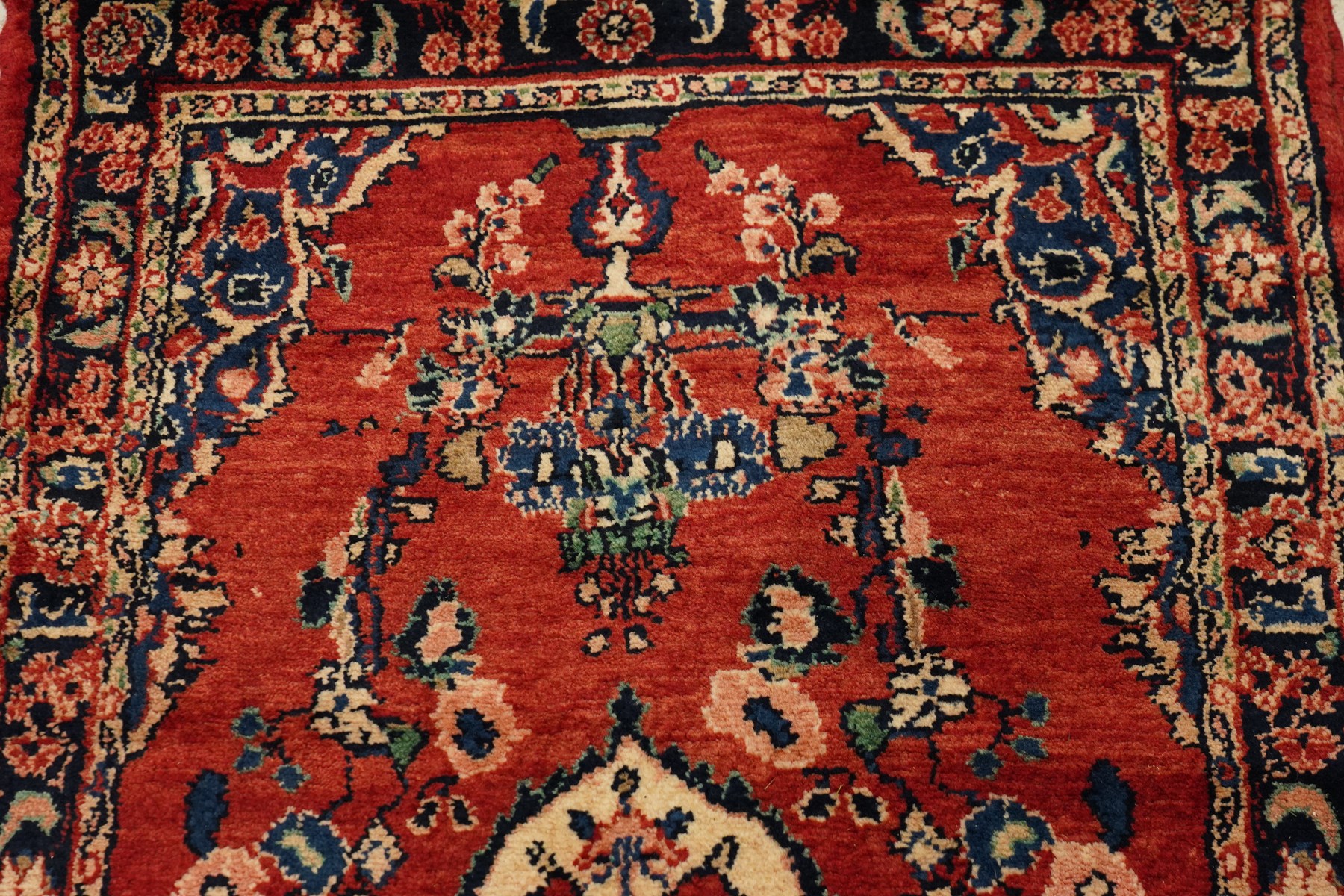 Persian Hamadan runner rug, the vermilion ground decorated with a row of ivory and indigo medallions interspersed with stylised flowering plants, indigo spandrels, enclosed by an indigo floral border and narrow patterned guard stripes
