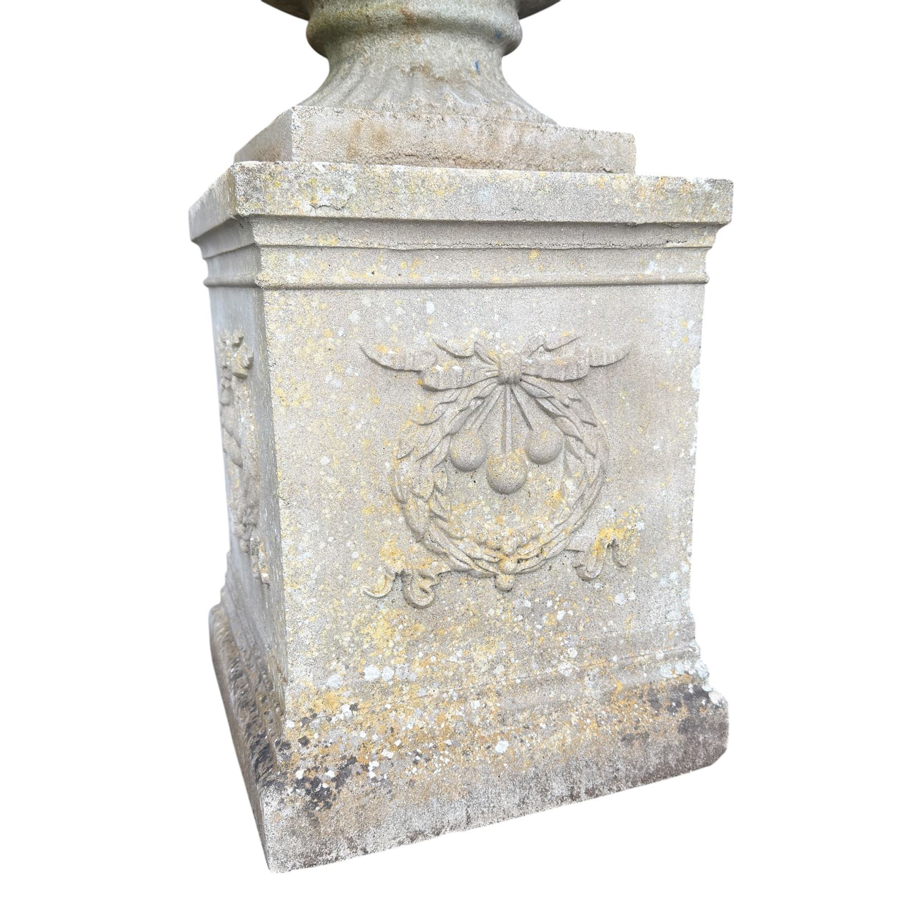 Pair of quality Neoclassical design Haddonstone cast stone garden urns, the globular  body decorated with relief foliate festoons and fruiting motifs, over a fluted socle, the rectangular pedestals with relief foliate wreaths and ribbon garlands