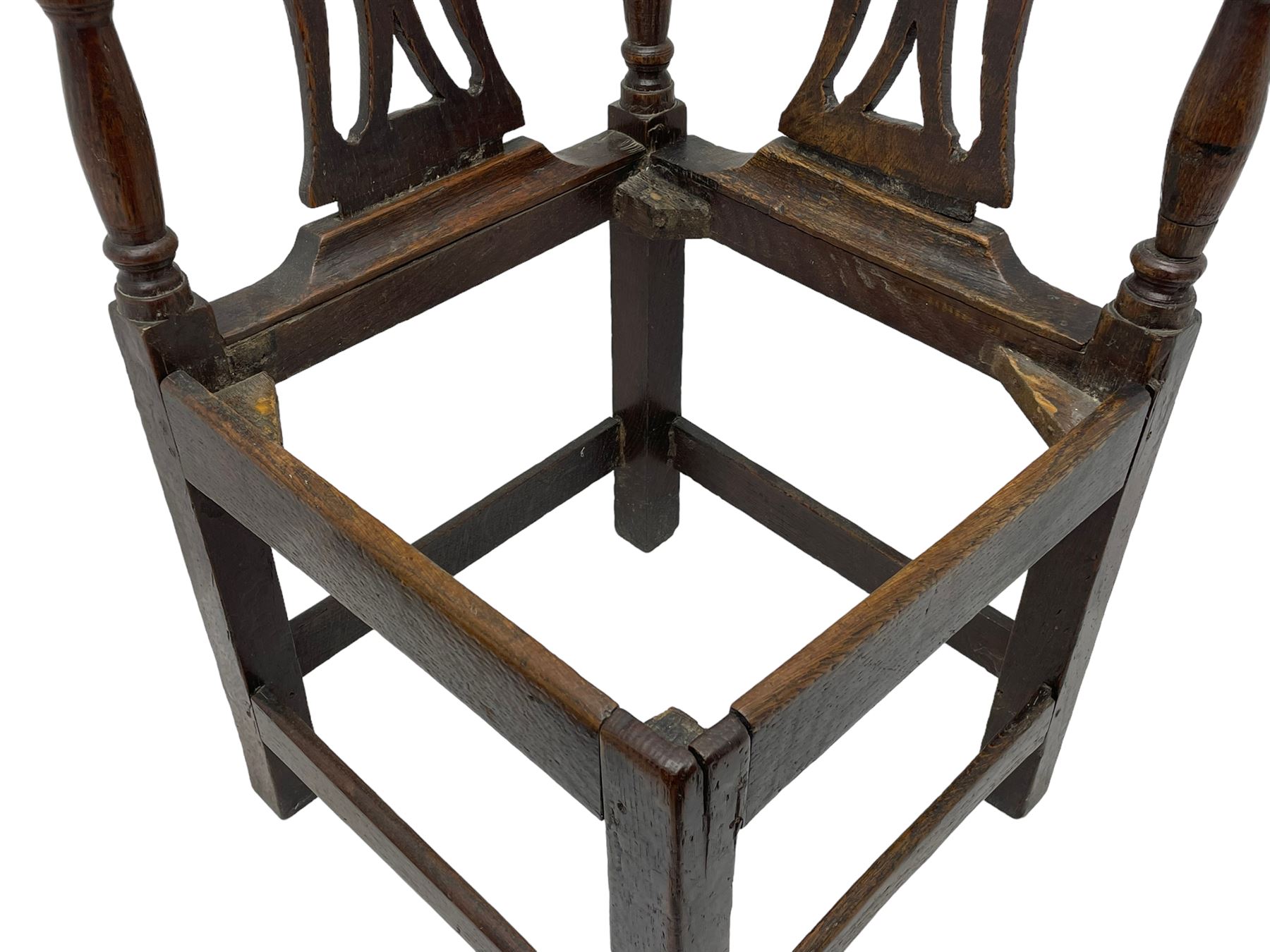 18th century country elm and oak corner chair, the shaped cresting rail terminating to swept arm resets, supported by turned columns and pierced shaped splats, over a drop-in rush seat, raised on square supports united by box stretcher