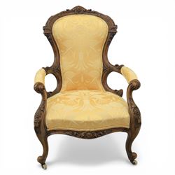Victorian carved walnut open armchair, shaped and moulded frame with foliate carved cresting rail, upholstered back and seat in yellow damask fabric, scroll arms with padded rests, carved cabriole supports terminating in ceramic castors