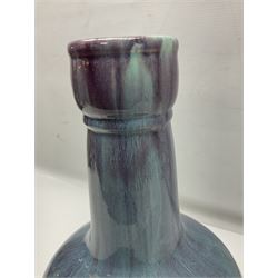 Blue glazed vase of squat baluster form with elongated neck, with merging streaked purple and light blue decoration, raised upon carved circular hardwood stand, H34cm