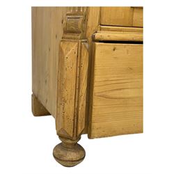 Late 19th century Continental pine vitrine, shaped and moulded arched cornice over a single glazed door enclosing adjustable shelves, flanked by carved pilasters with foliate and geometric motifs, fitted with single moulded drawer, raised on compressed bun feet