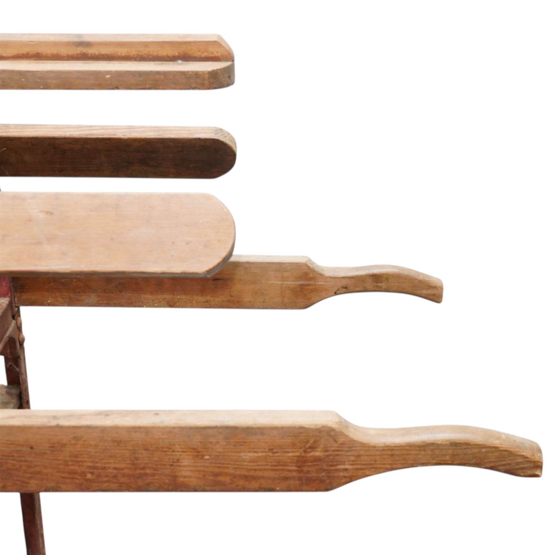 Cast iron and wooden saddle rack, arch form with shelf beneath and wheels to one end, pair of shaped handle poles