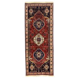 Fine Persian Qashqai crimson and navy ground runner, three large medallions filled with geometric and floral designs, the field with angular vines and stylised floral decoration, wide ivory border decorated with repeating floral and angular motifs