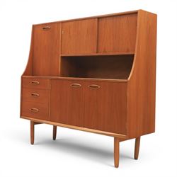 Jentique - mid-20th century teak highboard, fall front cabinet next to a sliding door cupboard above and open recess, the lower section with cabinet doors and three graduated drawers, raised on cylindrical legs