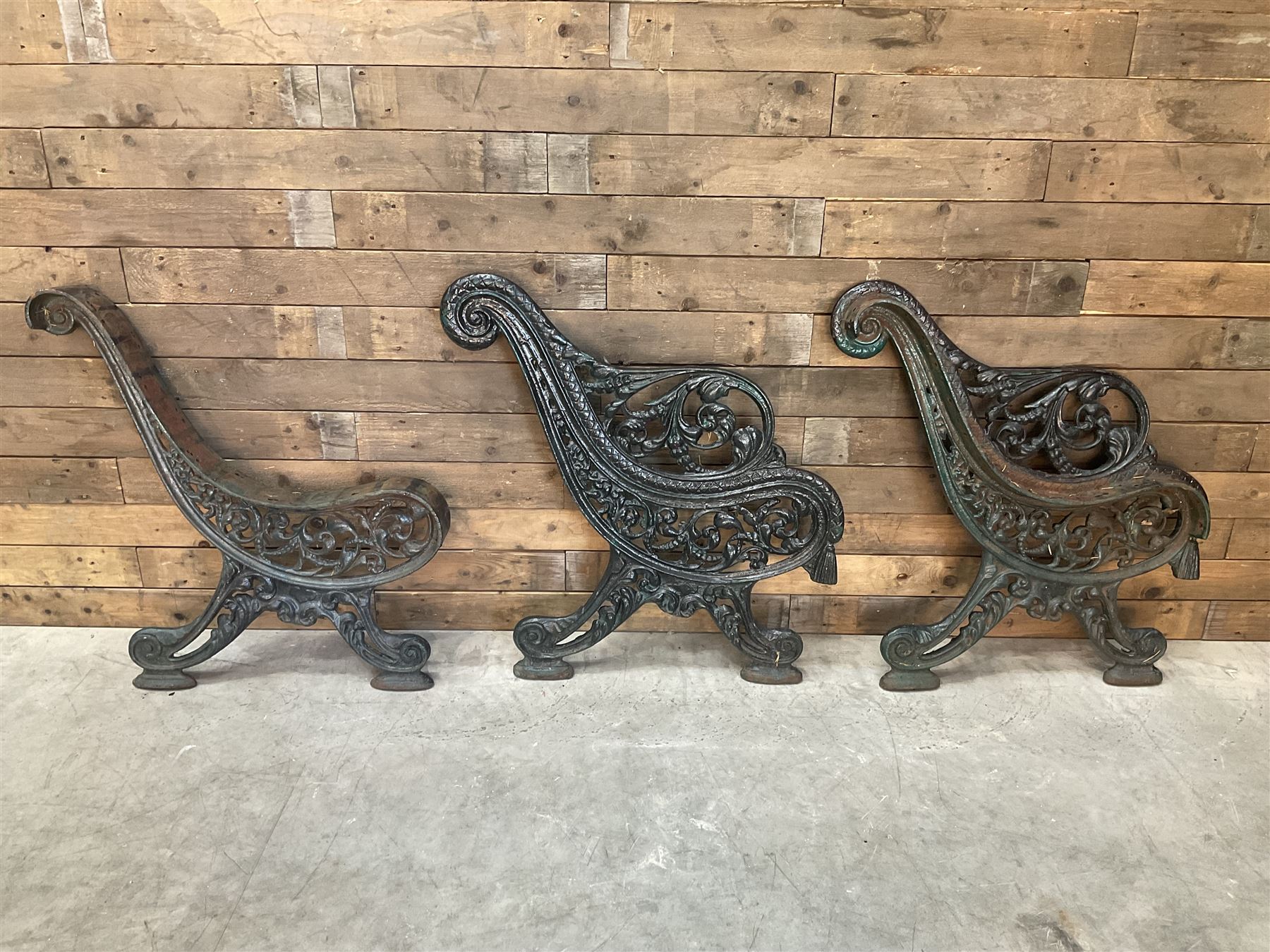 Early 20th century heavy cast iron three piece bench ends, decorated with scrolls and floral swags