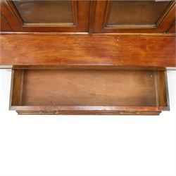 Victorian mahogany bookcase on cupboard of slender proportions, projecting cornice over dentil-frieze, fitted with twin-glazed doors enclosing three shelves, flanked by acanthus corbels, the base fitted with single frieze drawer over panelled cupboard, on skirted base