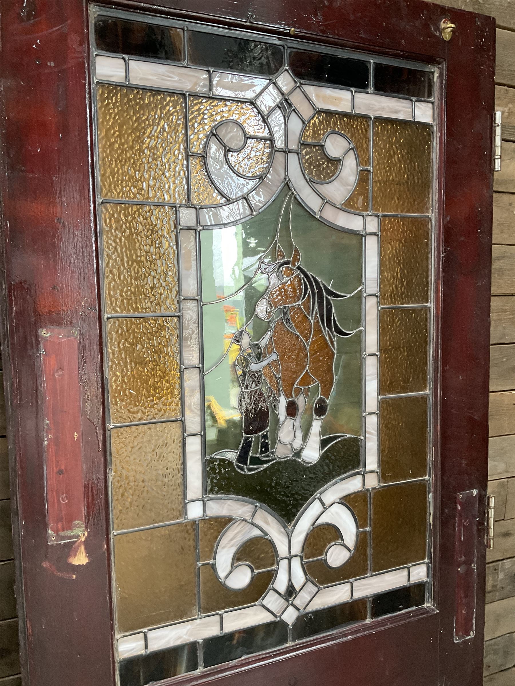 Two early to mid 20th century timber doors, set with lead framed stained glass panels depicting agricultural worker and horse
