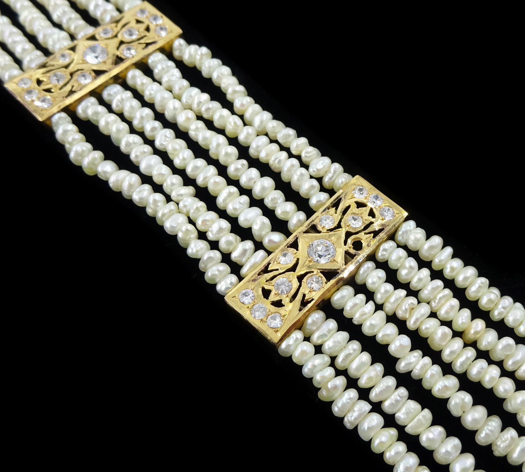 18ct gold pearl and white paste stone bracelet, six strands of cultured white pearls, spaced by openwork gold panels set with paste stones