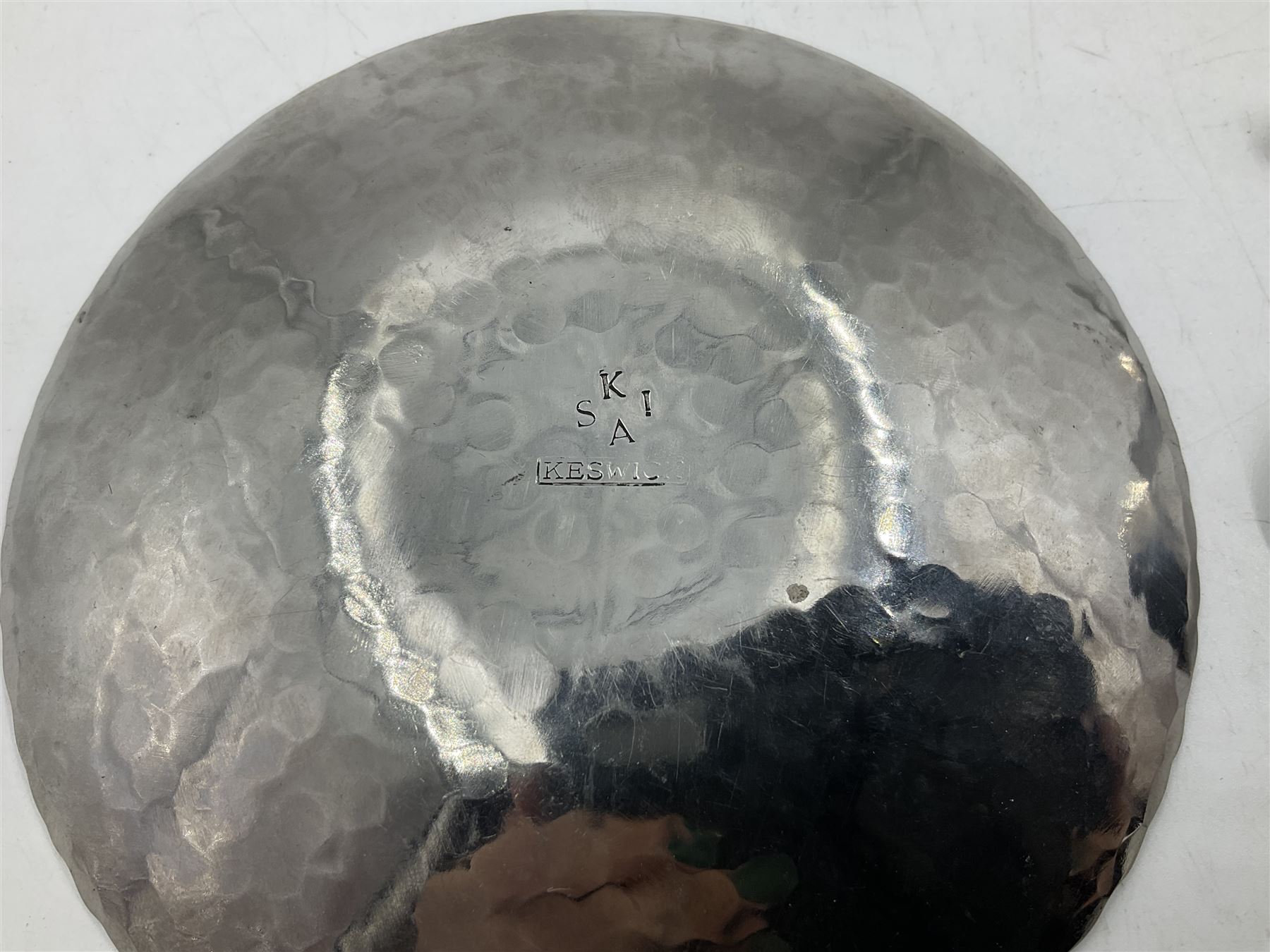 Keswick School of Industrial Arts (KSIA), Arts and Crafts hammered steel Staybrite caddy spoon, L6.5cm, and dish with engraved fern decoration to centre, D11.5cm, both with impressed marks beneath