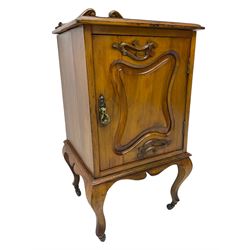 Edwardian Art Nouveau walnut bedside cabinet, raised broken swan neck back with carved flower heads, single fielded panelled door enclosing single shelf, raised on cabriole supports with ceramic castors