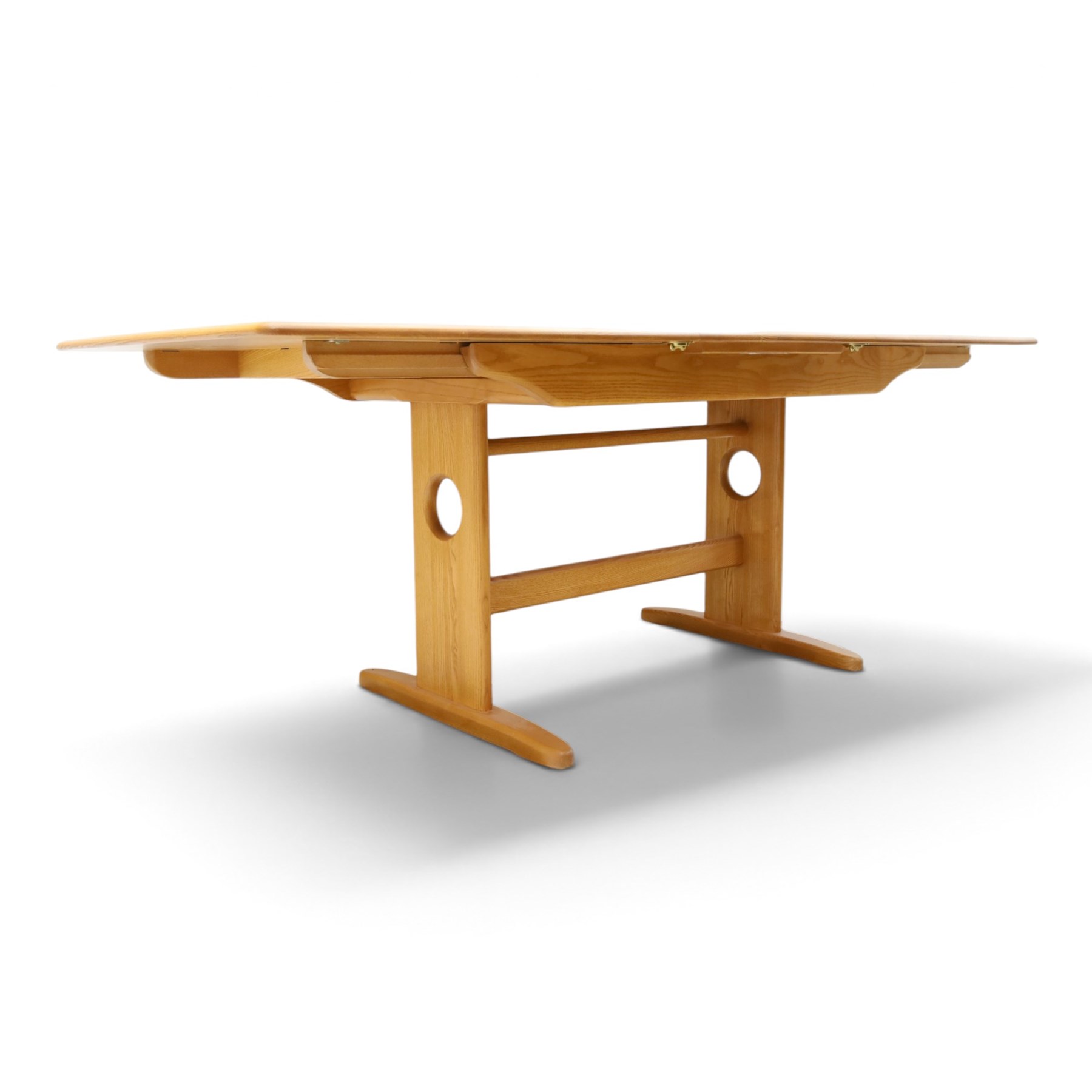 Ercol - 'Windsor' ash medium extending dining table, with stowed fold over leaf extending to 200cm, shaped supports with roundel aperture, united by a stretcher