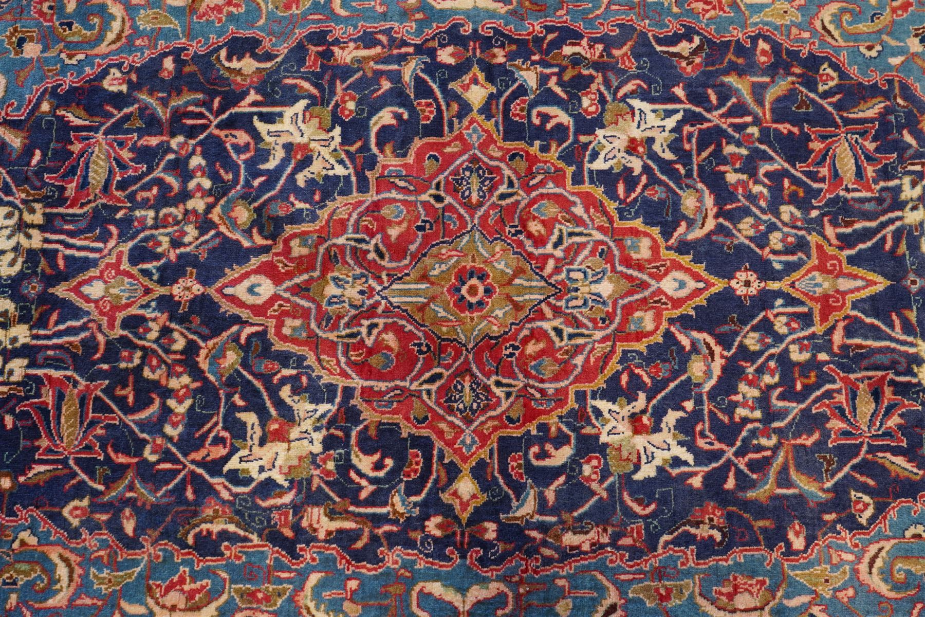 North West Persian Sarouk hand-knotted rug, indigo field with central stepped medallion with pendants, issuing an all-over arrangement of scrolling vinery, palmettes and stylized floral sprays, enclosed by a broad turquoise field of sinuous arabesques,, ivory spandrels with foliate decoration, madder red main border of stylized palmettes, and flowering vines, flanked by reciprocal guard stripes, cotton fringe ends 