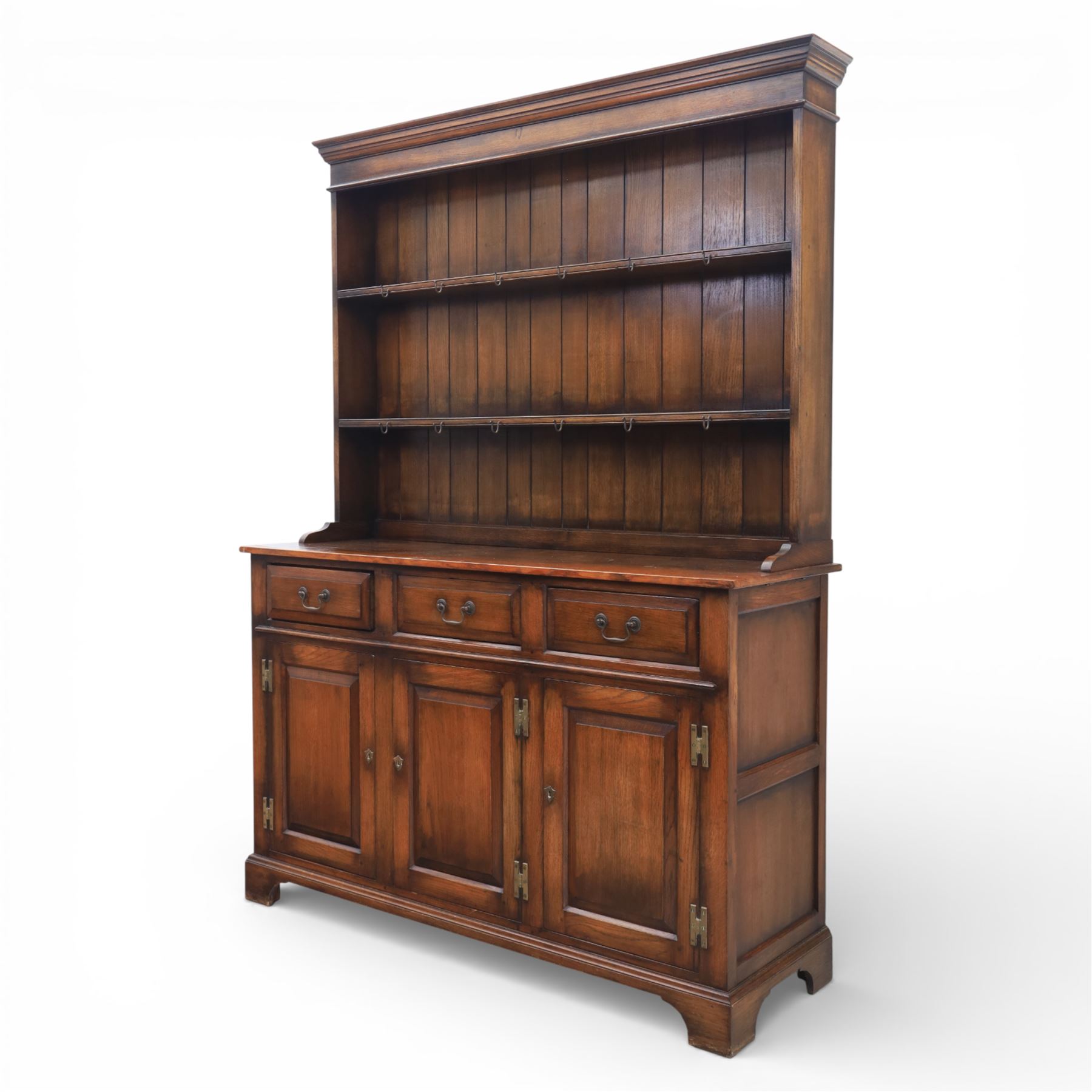 Georgian style oak dresser, the moulded cornice above two open plate racks, upon base with rectangular top above an arrangement of three frieze drawers fitted with brass swan neck handles, and three panelled cupboard doors, upon bracket feet