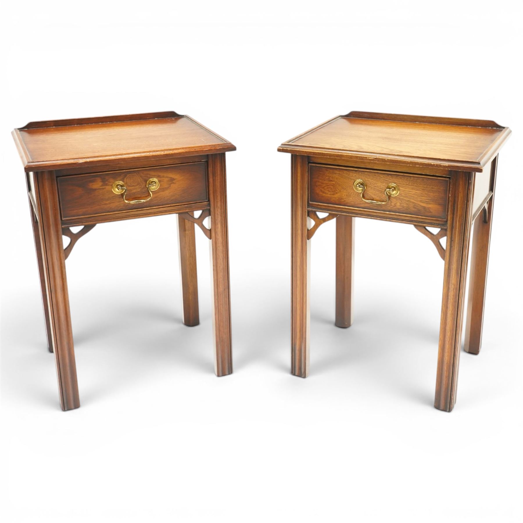 Pair of mahogany bedside tables, with quarter galleried top, single drawer with brass swan neck handle, pierced spandrels on fluted square supports  