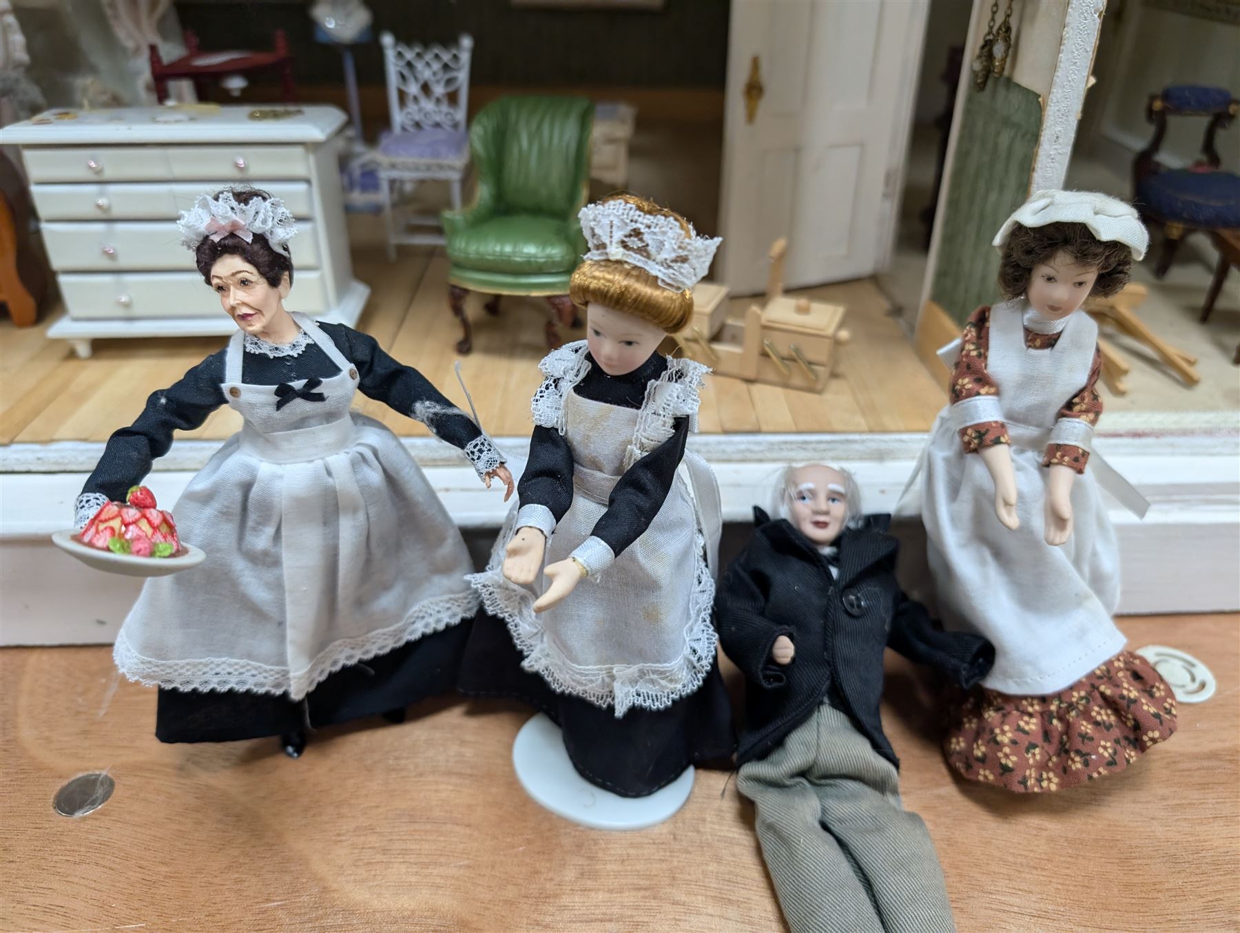 Two modern three storey dolls houses, each painted green with decorated interiors, both upon a single white wooden base, together with a large collection of dolls house furniture, accessories and figures 