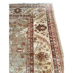 Pakistani ivory ground carpet, the field decorated with leaf branches, lotus flowers and roses, wide guarded border long leaves and stylised plant motifs