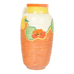 Clarice Cliff Nasturtium jug, shape Greek 563, hand painted with a band of stylised flowers and foliage over a stippled brown ground with orange and yellow banding to the spout,  Bizarre mark beneath, H23cm