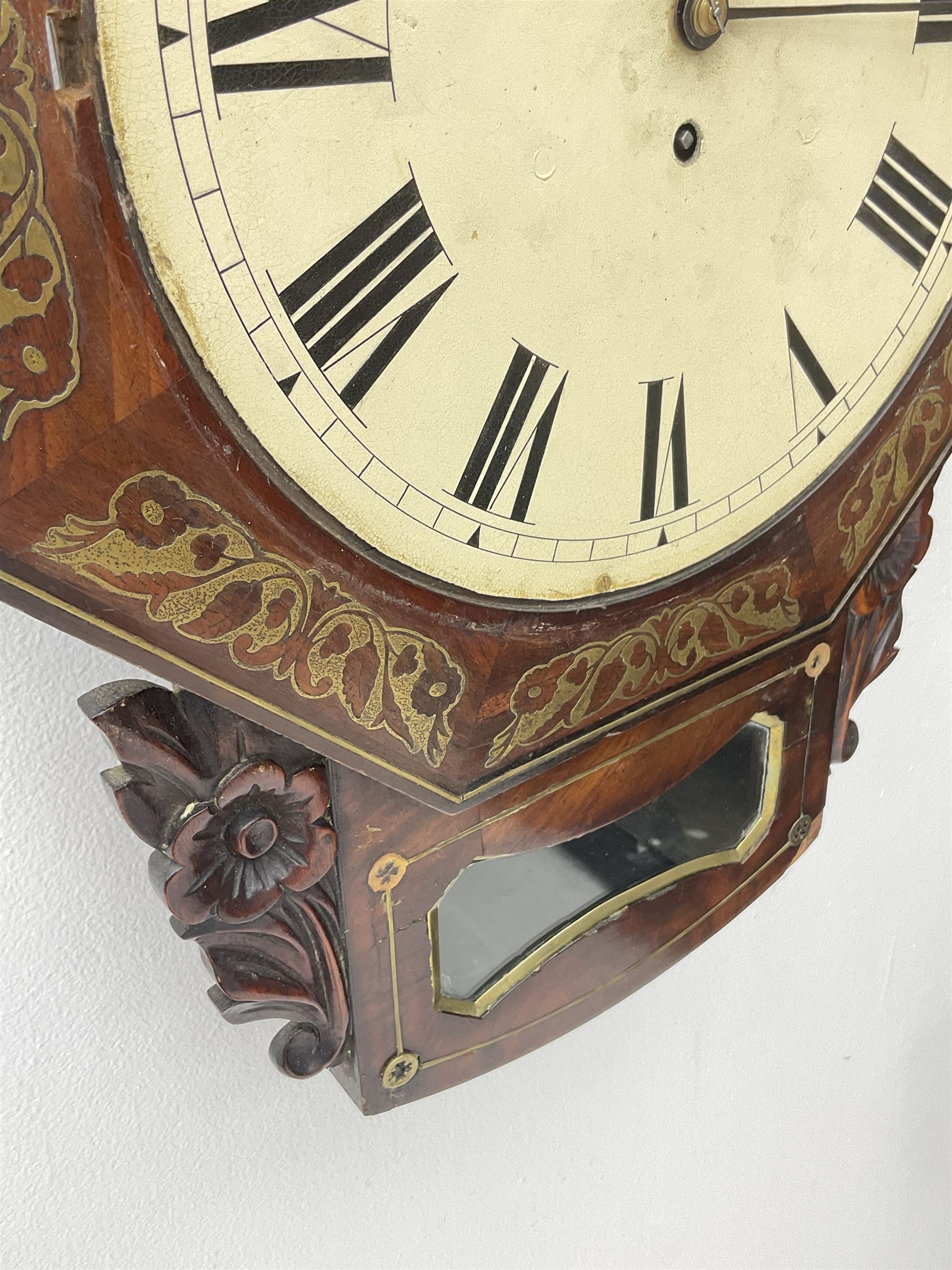 Mid-19th century mahogany veneered eight-day four-pillar single fusee drop dial wall clock with an octagonal dial surround and scroll brass inlay, circular painted steel dial with roman numerals and minute track, matching trefoil steel hands, brass bezel with a flat glass, curved trunk with brass inlaid circles and stringing around the glass pendulum aperture with a brass slip, carved ear pieces in the form of flowers and leaves, with pendulum adjustment door and movement door. With Pendulum & Key