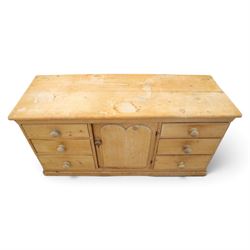 Victorian stripped pine sideboard, rectangular plank top rounded edges, with central cupboard door with shaped panel, flanked by two banks of three graduating drawers with turned knobs, raised on a plinth base 