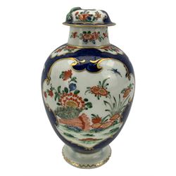 18th century Worcester tea caddy, of oval form and painted in the Kakiemon palette with reserves of flowers against a blue scale ground, H14cm together with a similar Worcester circular dish, painted with floral sprays, within a scalloped edge, blue crescent mark beneath, D19cm (2)