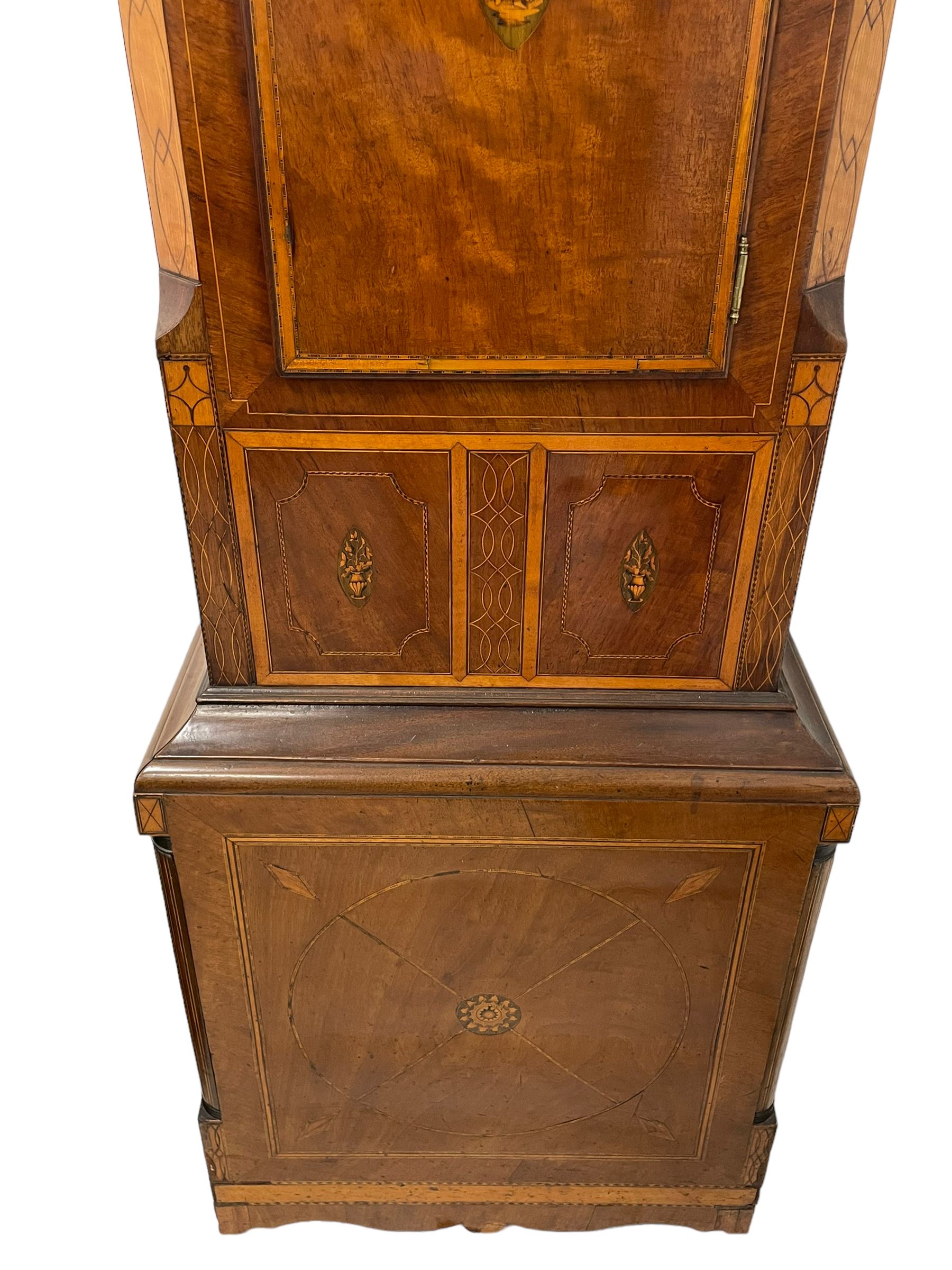 John Stonehouse of Leeds - mahogany 8-day longcase clock with a painted oval dial c1830, hood with a swans necked pediment and profuse contrasting inlay to both the hood and case, oval hood door with flanking pilasters and Corinthian capitals, conforming case with canted corners and short triple spire door, broad plinth with matching inlay and canted corners on shallow base, dial depicting masonic regalia, symbols, and pictorial depictions of the humanities, faith, hope, charity and righteousness, black chapter with white roman Arabic’s, date recorder and matching “crown” hands, dial pinned to a rack striking movement with a recoil anchor escapement, striking the hours on a coiled underslung gong. With weights and gridiron pendulum. 
This clock case is of large, impressive dimensions and was almost certainly commissioned for a large masonic lodge in Leeds, a rare and unique example.