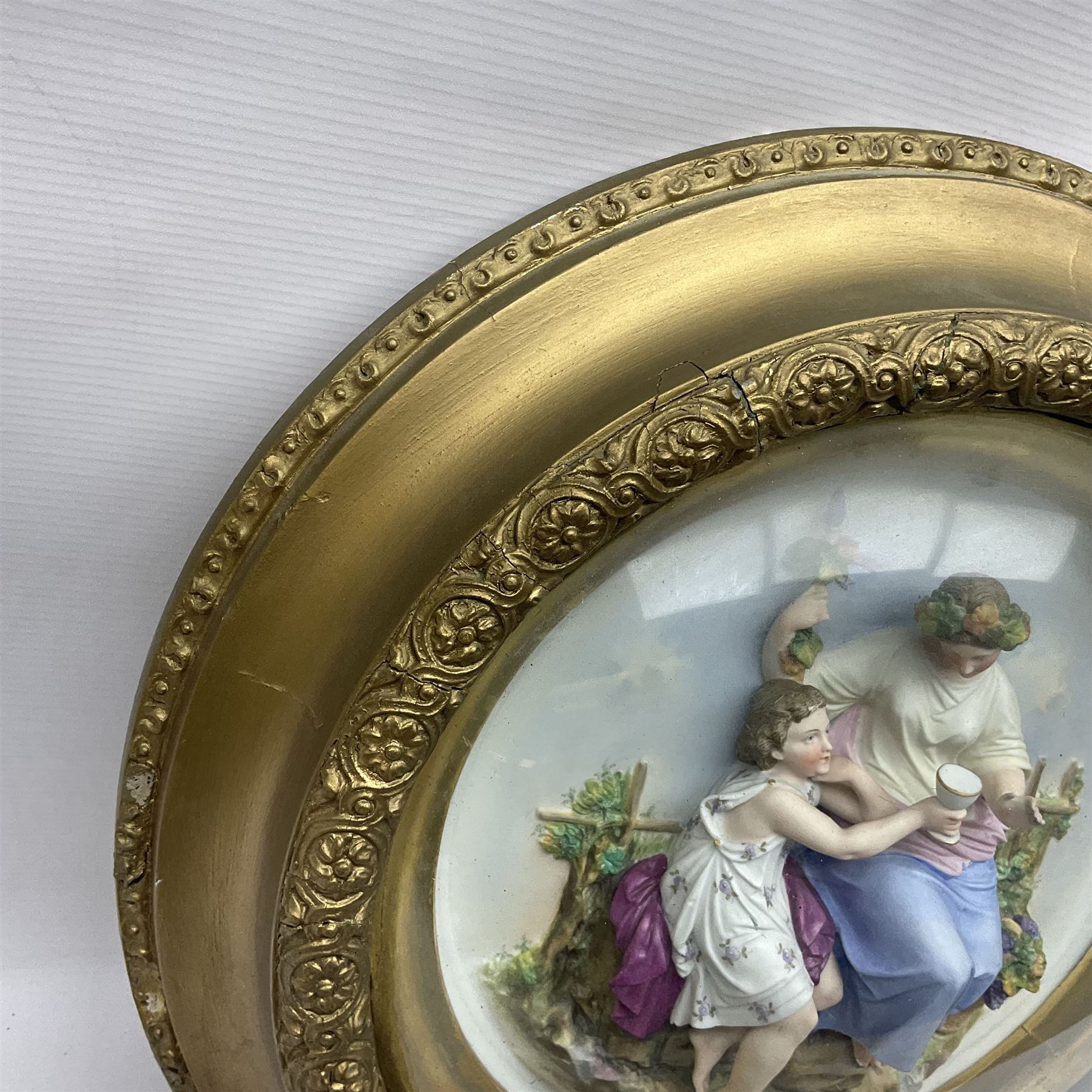 Set of four early 20th century Continental bisque plaques, each of circular form, modelled in high relief as the Four Seasons personified, within gilded circular frames under convex glass, overall D44.5cm