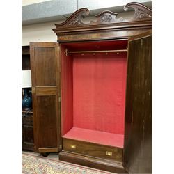 Late Victorian walnut triple wardrobe, the pierced broken swan neck pediment carved with foliate C-scrolls, central bevelled mirror door flanked by two panelled doors, the panels carved with urns, C-scrolls and trailing foliage, the interior fitted with hanging rails, long and short drawer, on moulded plinth base