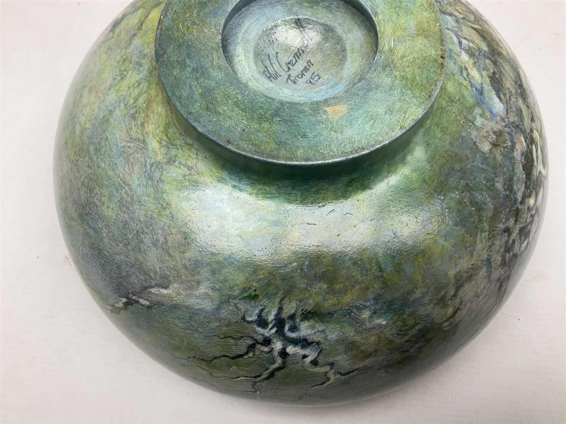 Wooden hand painted bowl, decorated with trees on a blue ground, signed Phil Crennell beneath, D28cm