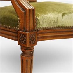 French Louis XVI style walnut armchairs, rectangular upholstered backs with nailhead trim, padded seats upholstered en suite, out-swept arms with upholstered pads, fluted supports with carved rosettes to the knees, on turned and fluted tapering legs