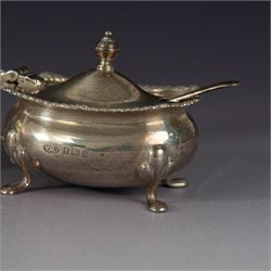 Mid 20th century silver three piece cruet set, comprising pepper shaker, open salt, mustard pot with cover and two condiment spoons, all of oval form with oblique gadrooned rims and upon four paw feet, hallmarked Adie Brothers Ltd, Birmingham 1957, with blue glass liners