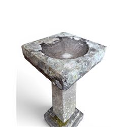 19th century weathered sandstone birdbath, formed in four sections, square top with carved shell bath, raised on tapering column with stepped base