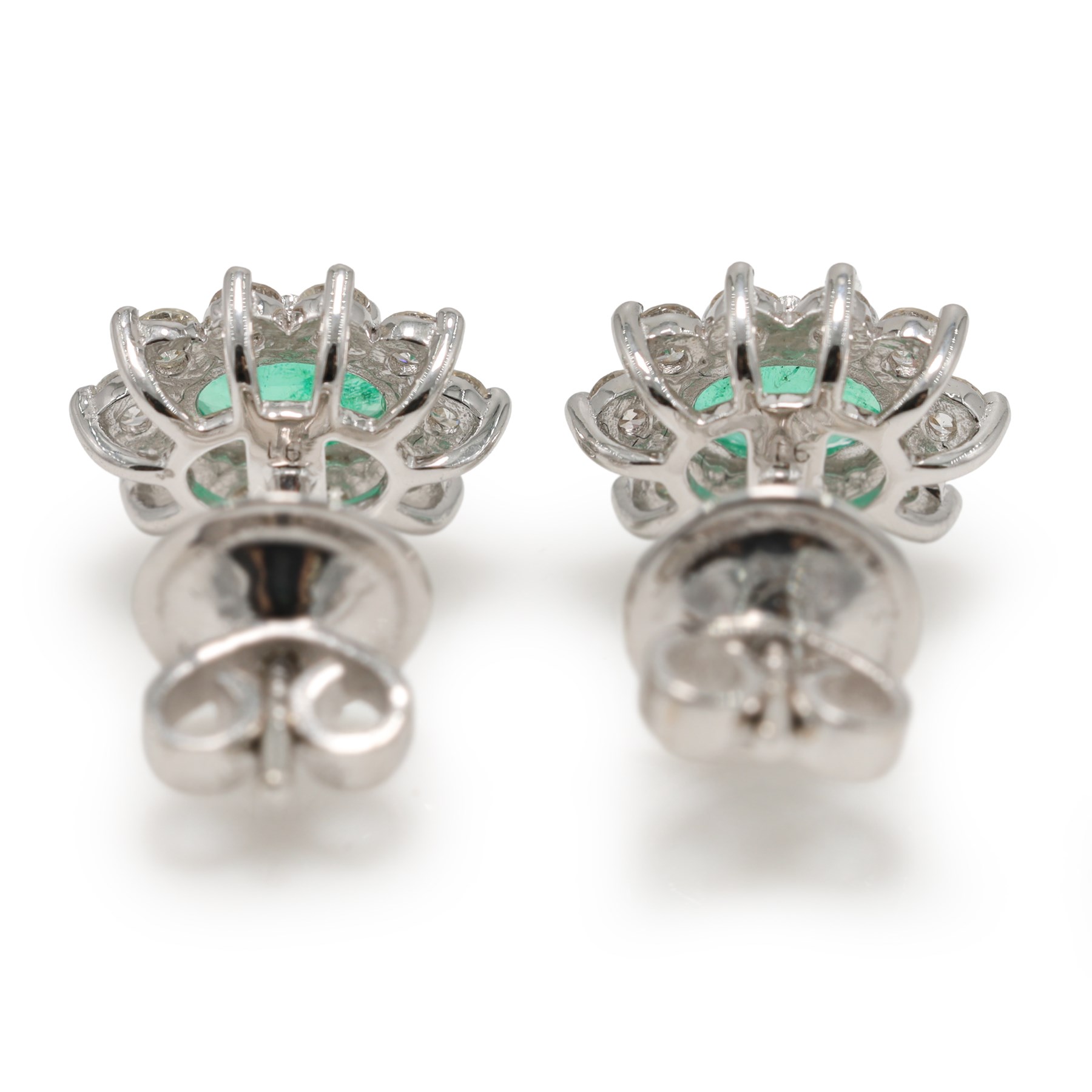 Pair of 18ct white gold emerald and diamond cluster earrings, each stud set with a single oval cut emerald surrounded by round brilliant cut diamonds, stamped, total emerald weight approx 0.75 carat, total diamond weight approx 0.55 carat