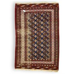 Persian indigo Bokhara rug, decorated with three rows of Gul motifs, within multiple band border 
