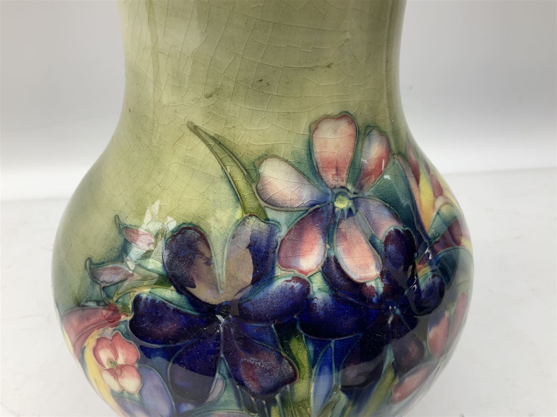 Moorcroft vase of baluster form decorated in the Spring Flowers pattern upon a merging green and blue ground, with impressed and painted marks beneath, H22.5cm