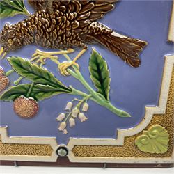 19th century Minton & Co majolica tile, decorated in relief with a bird upon a fruiting branch against a blue ground, with textured ochre border and anthemion to each corner, impressed mark verso, H19.7cm