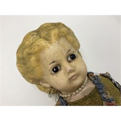 Victorian large wax over composition Pumpkin head doll, with inset dark glass eyes, moulded blonde hair in curls, stuffed body with carved and painted wooden limbs, grey painted boots, floral satin dress with netting underclothes H61cm