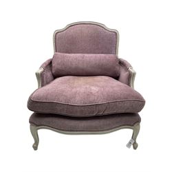 Louis XVI style bergere enclosed armchair, white finish shaped and moulded frame carved with scroll and foliate detail, upholstered in purple fabric with loose seat cushion and additional bolster cushion, serpentine seat, on cabriole supports