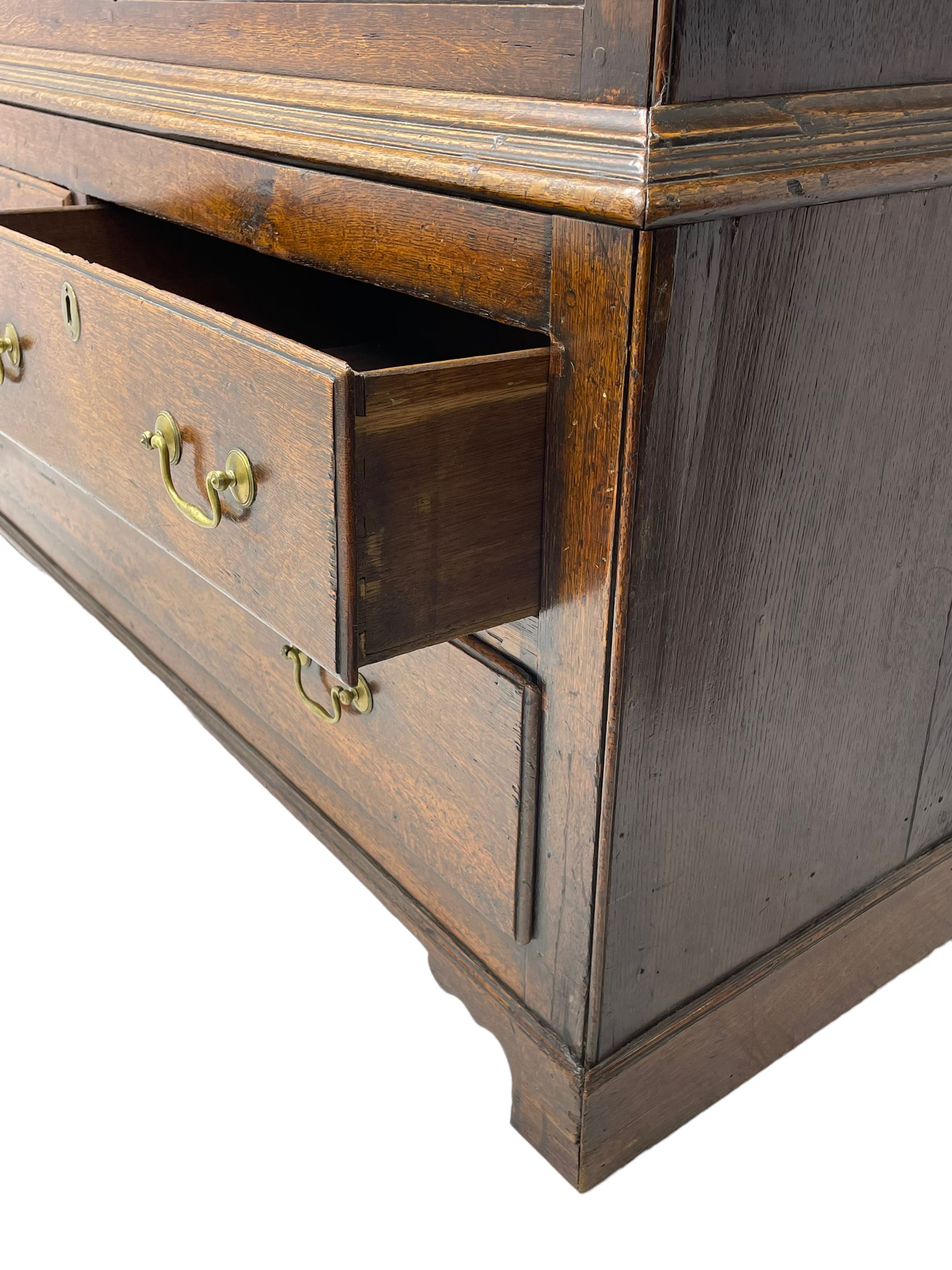 George III oak livery cupboard, projecting moulded cornice over two panelled doors, the upper panels within stepped ogee and arched moulded frame, the interior fitted with a single row of wooden hooks, two short and one long drawers, on bracket and return skirted base 