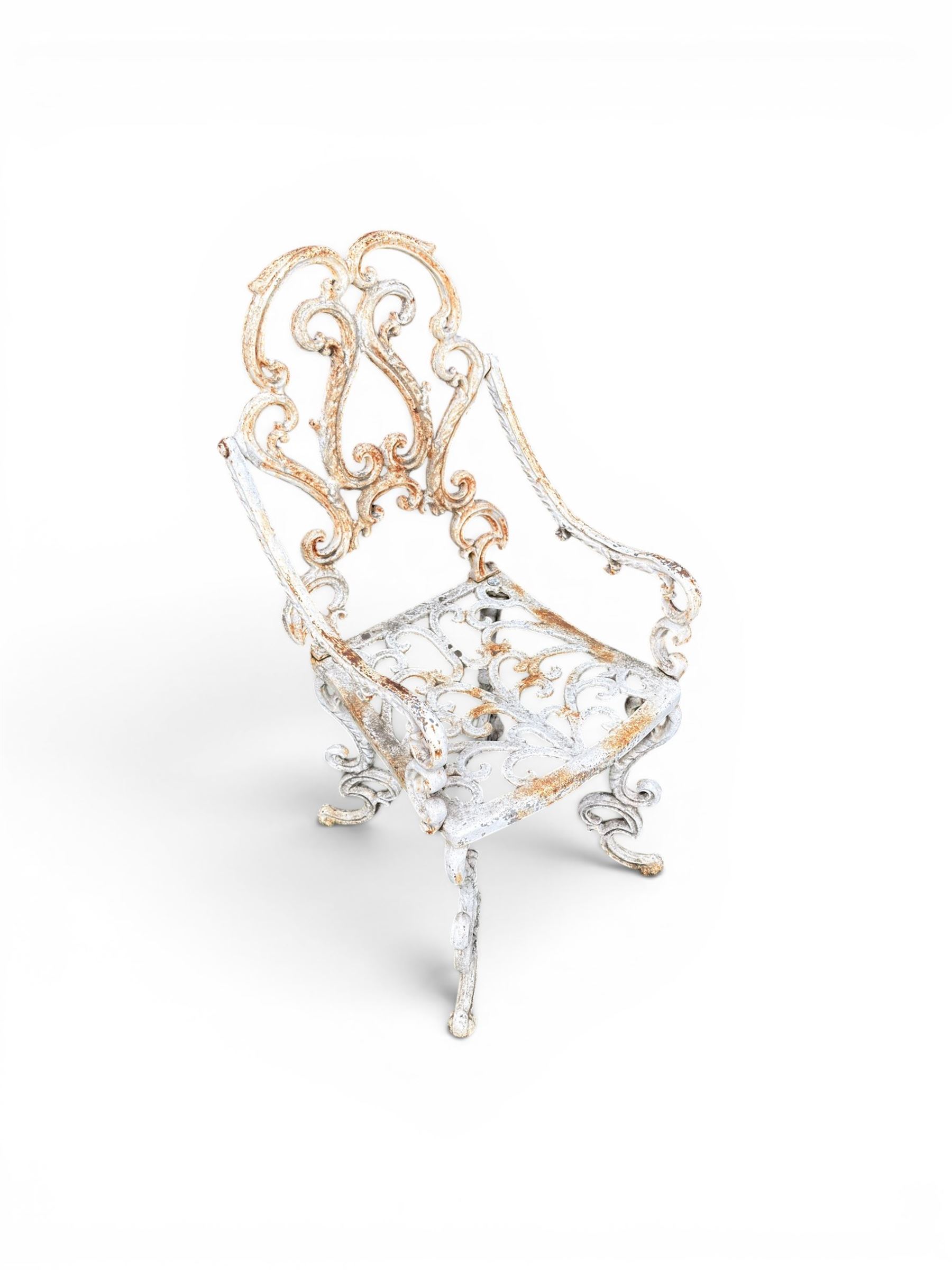 Pair of Victorian cast iron garden chairs, the ornate pierced back of scrolling foliate design, scrolling arm terminals over splayed supports formed of C and S-scrolls, in distressed white painted finish