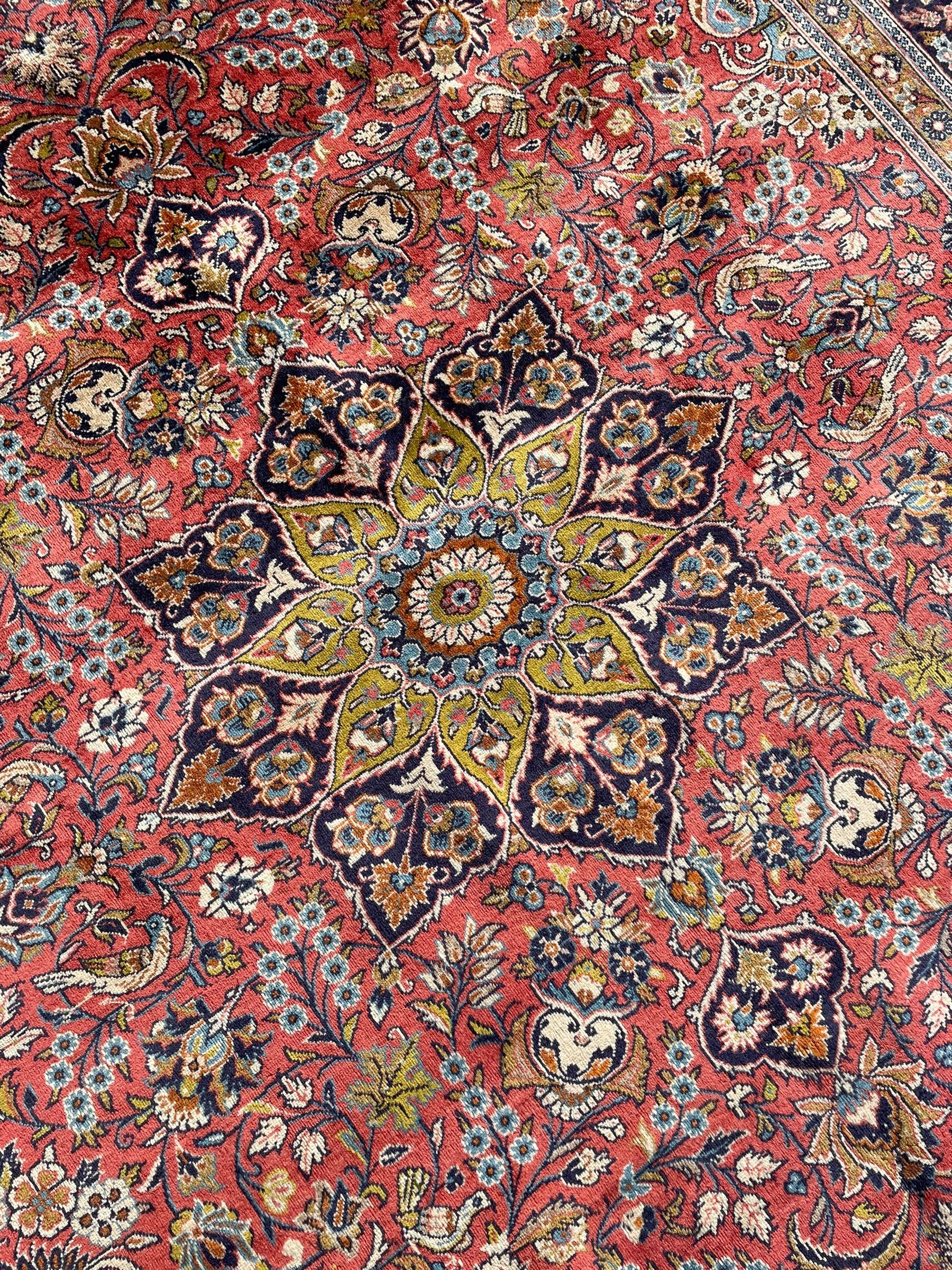 Persian Kashan peach ground rug, central rosette medallion surrounded by trailing branches and flower heads with bird motifs, light blue spandrels with further floral decoration, the main border with repeating palmettes and birds, within guard stripes