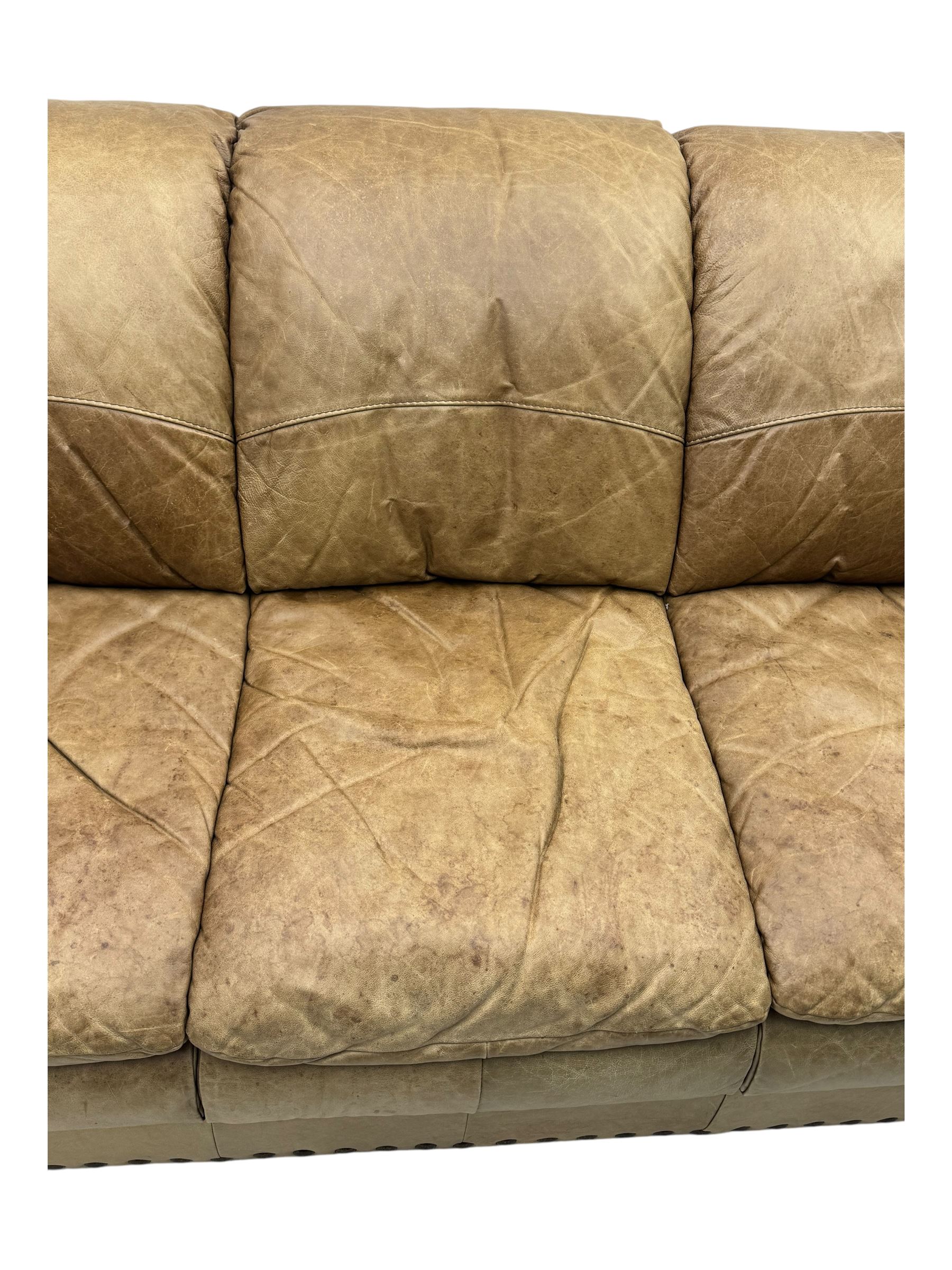Contemporary three-seat sofa, upholstered in stitched brown leather with brass studwork decoration, rolled back and arms, raised on turned supports