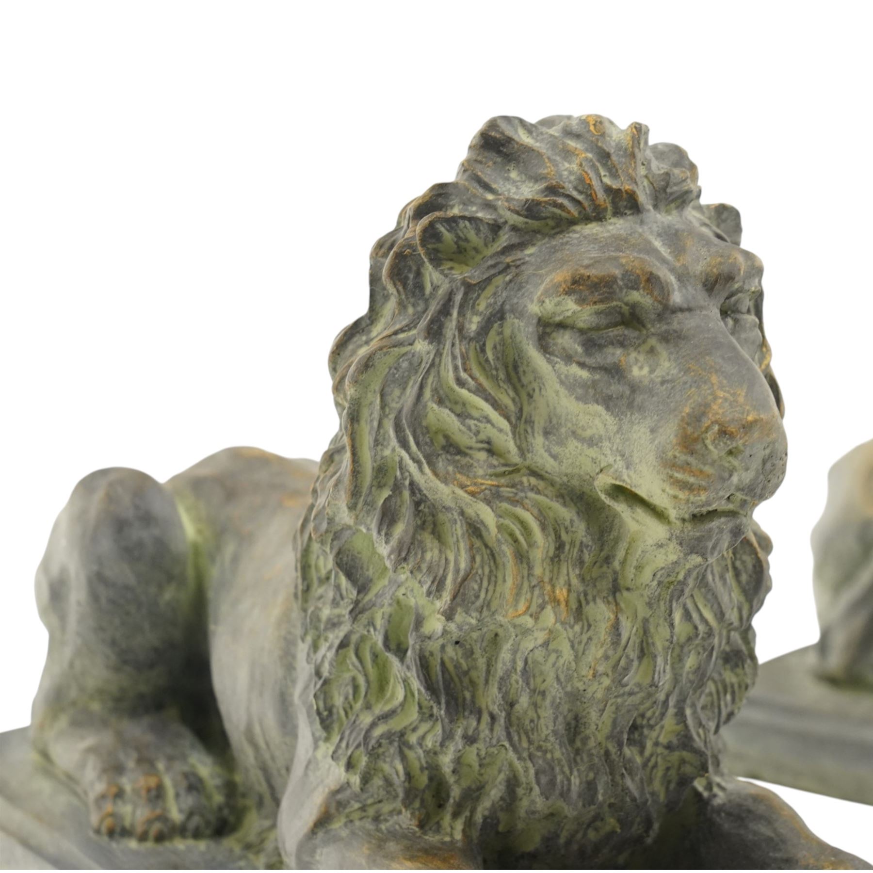 Pair of bronze-effect composition stone recumbent lions, with verdigris-style weathered finish, each raised on rectangular plinth base