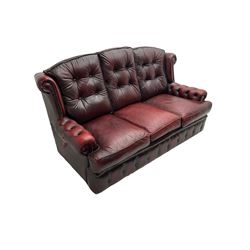 Mid-20th century three seat wing back sofa, upholstered in oxblood buttoned leather with studwork, on shepherd castors; pair matching mid-20th century chesterfield style armchairs (90cm x 88cm x 98cm)