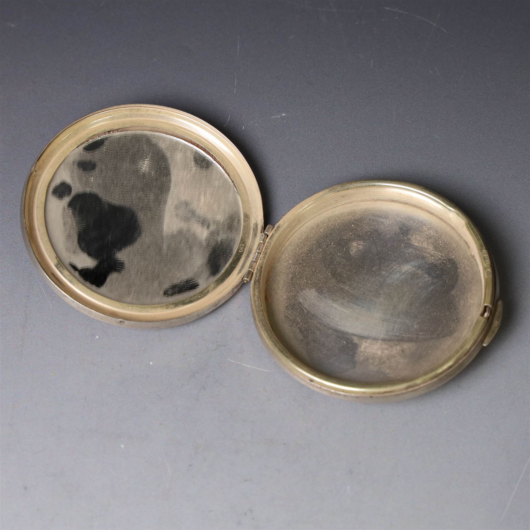 1960s silver compact mirror, of circular form with engine turned and engraved foliate decoration to lid, hallmarked Kigu Ltd, London 1963 and an early 20th century silver cigarette case with engraved monogram to cover, hallmarked A J Pepper & Co, Birmingham 1918
