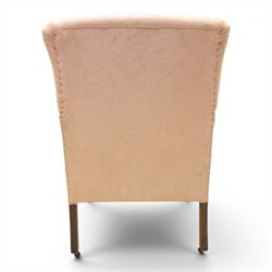 Edwardian mahogany framed armchair of traditional shape, high sprung back and seat over squared padded arms, upholstered in foliate patterned pale pink upholstery, on square tapering supports with brass castors