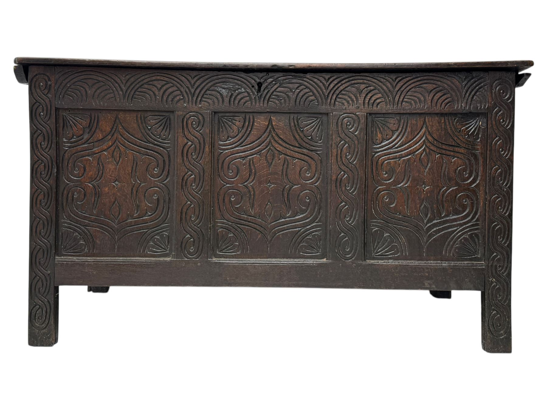 English carved oak coffer, hinged rectangular lid with indented side edges, internal candle-box, front with three-panel front with decorative carvings, raised on stile feet, circa 1700